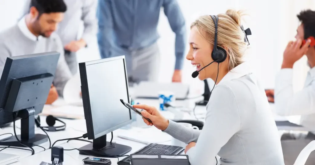 Smiling technical support agent wearing a headset while working on a computer