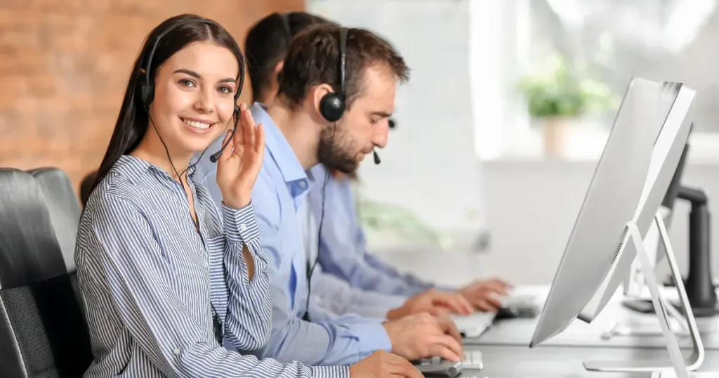 Smiling technical support agent wearing a headset while working on a computer